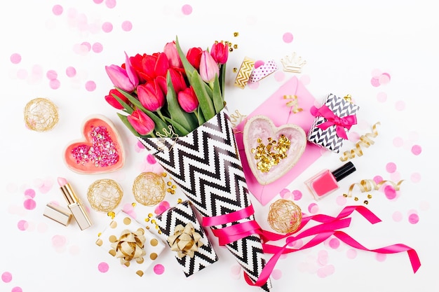 escritorio de estilo rosa y dorado con flores, tulipanes rosados, cosméticos y accesorios femeninos