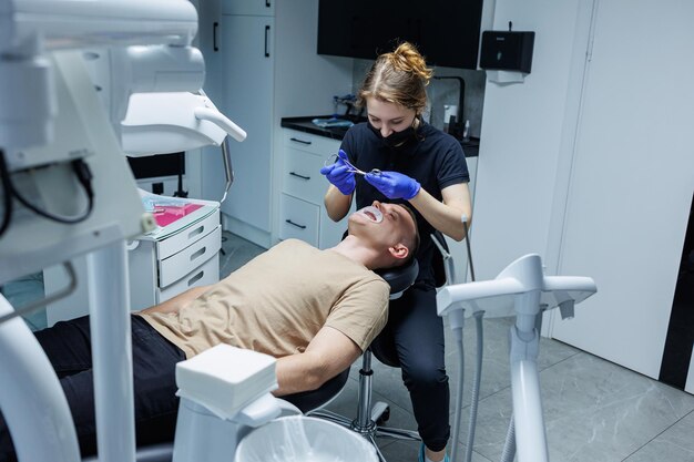 Escritório estomatológico moderno Um ortodontista instala aparelhos ortopédicos Tratamento de dentes de uma pessoa com uma mordida incorreta Tratamento dos dentes
