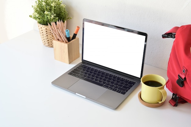 Escritorio de estudiante con laptop de pantalla en blanco,