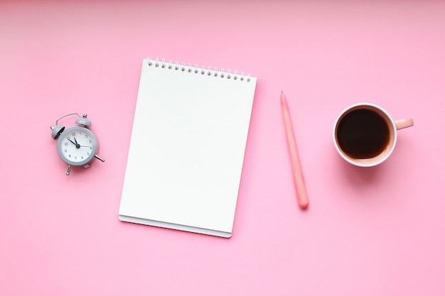 Escritorio para estudiantes con útiles, cuaderno, taza de café, bolígrafo, mini reloj despertador.