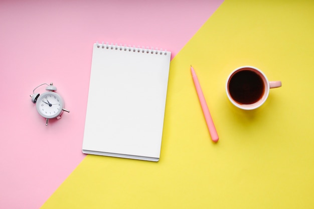 Escritorio para estudiantes con útiles, cuaderno, taza de café, bolígrafo, mini reloj despertador.