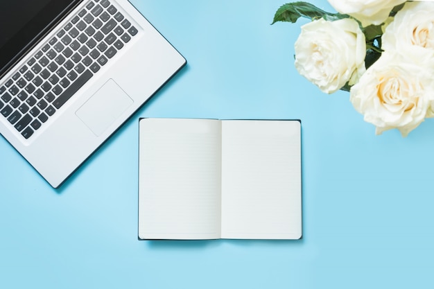 Escritorio femenino con una computadora portátil y flores en azul