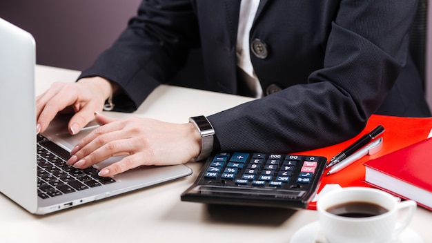 Escritório feminino mãos laptop calculadora café