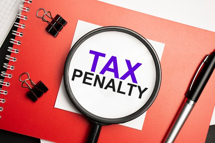 En el escritorio hay informes, blocs de notas, una calculadora, un dinero en efectivo y una pegatina amarilla con el texto PENALIDAD DE IMPUESTOS. Concepto de negocio