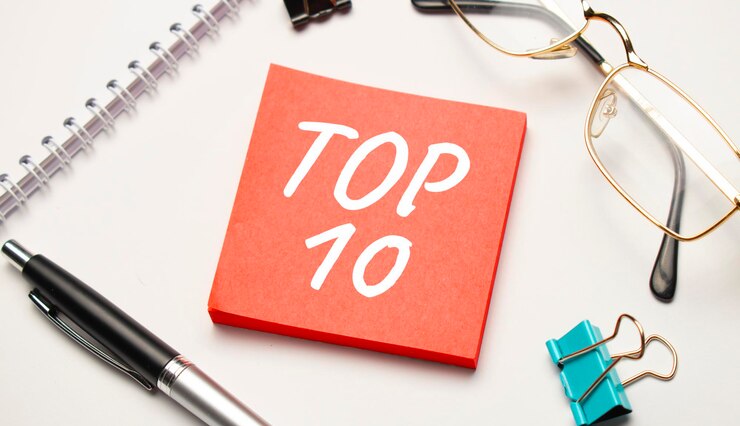 En el escritorio hay informes, blocs de notas, una calculadora, dinero en efectivo y una pegatina roja con el texto Top 10 Business Concept