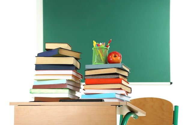 Escritorio de madera con libros y silla en clase con fondo de pizarra