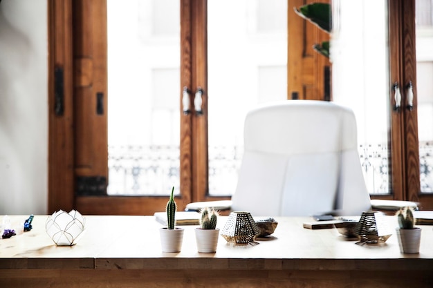 Escritorio de madera con velas de cactus y una silla blanca.