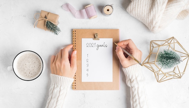 Foto escritorio de manos de mujer con bloc de notas en blanco escribir texto de objetivos