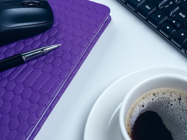 Escritorio de mesa de oficina. Espacio de trabajo con cuaderno, teclado, material de oficina y taza de café sobre fondo blanco.
