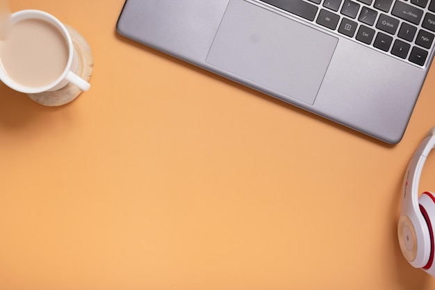 Escritorio de mesa de oficina plano Espacio de trabajo con beckground naranja en blanco y vista superior de auriculares de taza de café