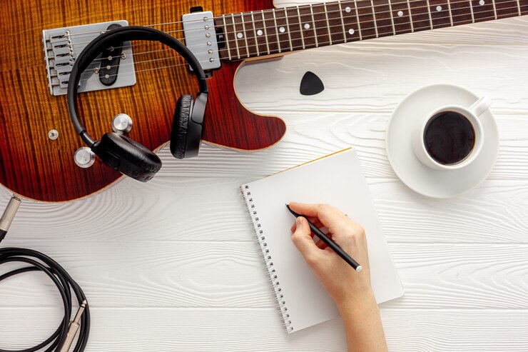 Foto escritorio de músico para trabajo de compositor con auriculares y guitarra