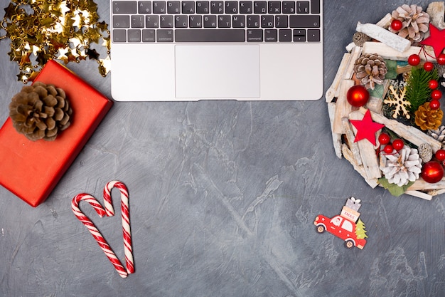 Foto escritorio navideño con laptop, corona, caja de regalo y bastón de caramelo