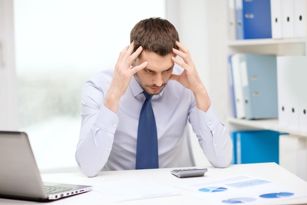 Escritório, negócios, tecnologia, finanças e conceito de internet - empresário estressado com laptop e documentos no escritório