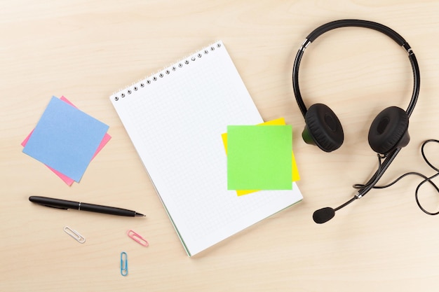 Escritorio de oficina con auriculares y suministros.