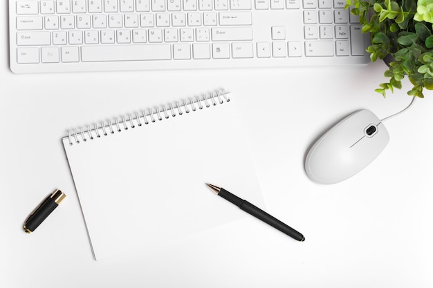 Escritorio de oficina blanco moderno con teclado y suministros.