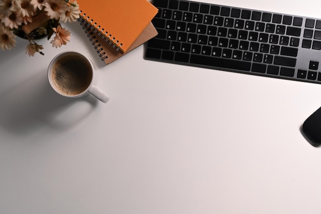 Escritorio de oficina blanco de vista superior con teclado inalámbrico taza de café y cuaderno Copiar espacio para texto