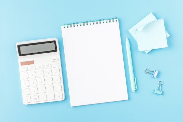 Escritorio de oficina con calculadora, bloc de notas y gafas