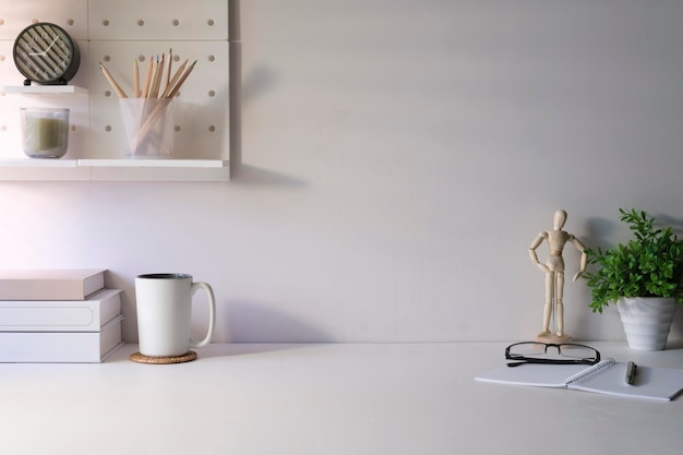 Escritorio de oficina en casa con marco de imagen de papelería y planta en maceta en mesa blanca Espacio de copia