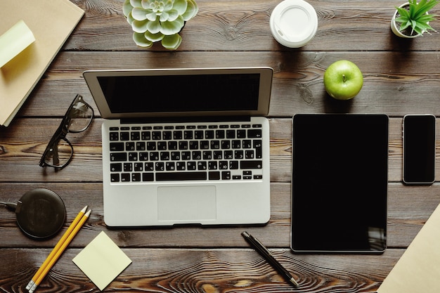 Escritorio de oficina con computadora portátil, suministros y manzana verde, vista superior