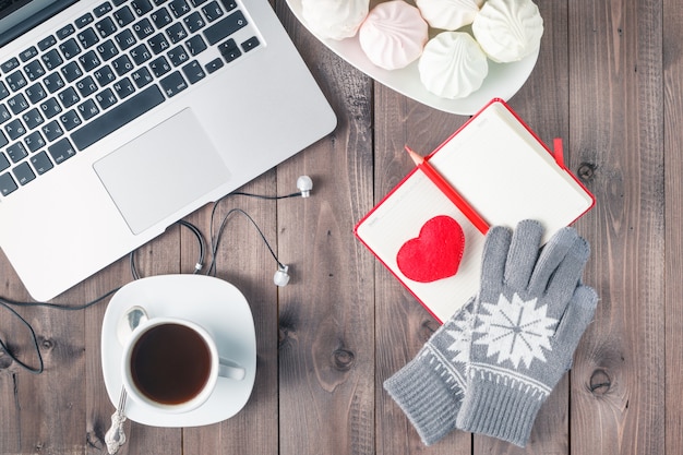 Escritorio de oficina con corazón rojo, cuaderno y dulces. Concepto de día de San Valentín