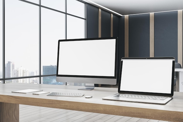 Escritorio de oficina de diseñador contemporáneo con suministros de pantallas de computadora de maquetas blancas vacías e interior borroso con ventanas y fondo de vista de la ciudad 3D Rendering