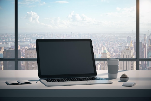 Escritorio de oficina de diseño moderno con pantalla de computadora portátil limpia, taza de café, algunos suministros y vista panorámica de la ciudad con luz natural, maqueta de renderizado 3D
