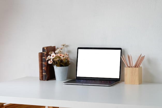 Escritorio de oficina un espacio de trabajo con laptop, libros, flor y lápiz. Pantalla de montaje.