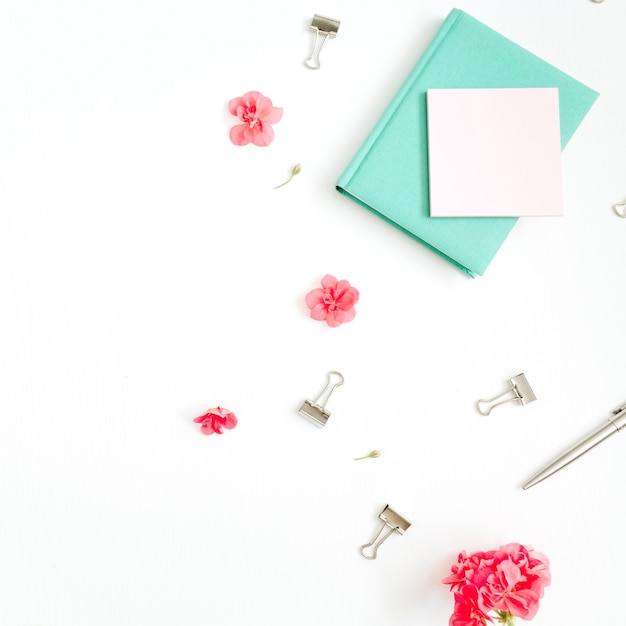 Escritorio de oficina de moda laicos plana. Espacio de trabajo femenino con flores rojas, accesorios, diario de menta en blanco