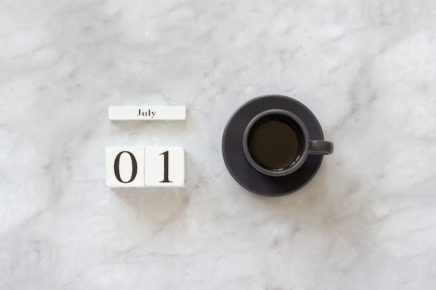 Escritorio de oficina o mesa en casa. Calendario de cubos de madera 1 de julio y taza de café sobre fondo de mármol Concepto elegante lugar de trabajo