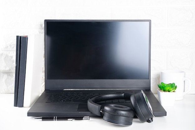 Foto escritorio de oficina simple. computadora portátil, auriculares y taza de café o té