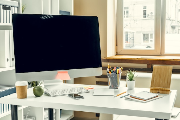 Escritório ou espaço de trabalho em casa. Monitor de computador com tela preta na mesa de escritório com suprimentos