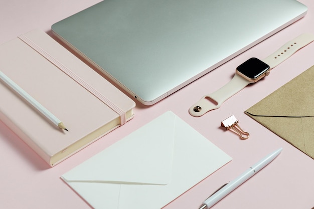 Escritorio rosa femenino con laptop y papelería.