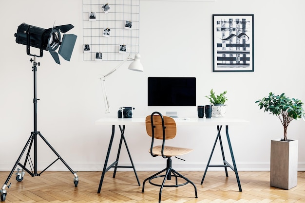 Escritorio y silla entre planta y lámpara en interior de autónomo blanco con carteles Foto real