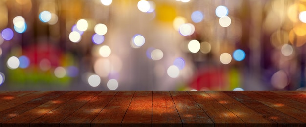 escritorio superior con fondo de restaurante borrosoMesa de madera y bokeh borroso de fondo de la calle nocturna
