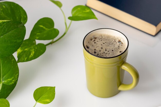 Escritorio con una taza de café al lado de una planta y dos libros en el fondo con espacio para copiar