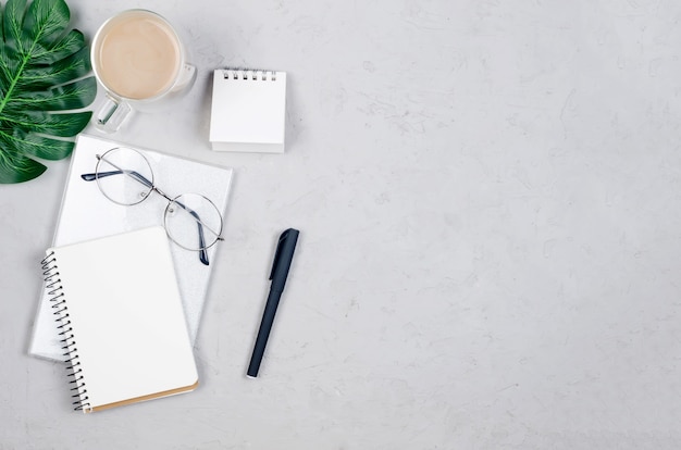 Escritorio de trabajo con cuadernos, espacio en blanco vacío, suministros, vasos y taza de café