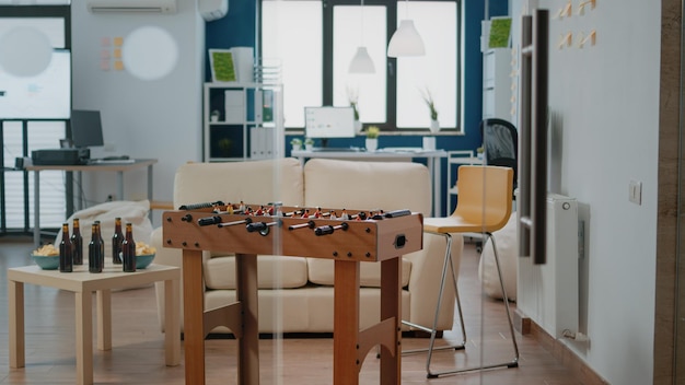 Escritório vazio preparado para bebidas e atividades divertidas após o expediente. Ninguém no local de trabalho com mesa de jogo de futebol, lanches e garrafas de cerveja para festa de confraternização com os colegas depois do trabalho.