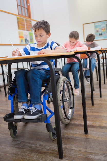 Escritura del alumno discapacitado en el escritorio en el aula