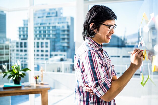 Escritura creativa del hombre de negocios en notas pegajosas en oficina