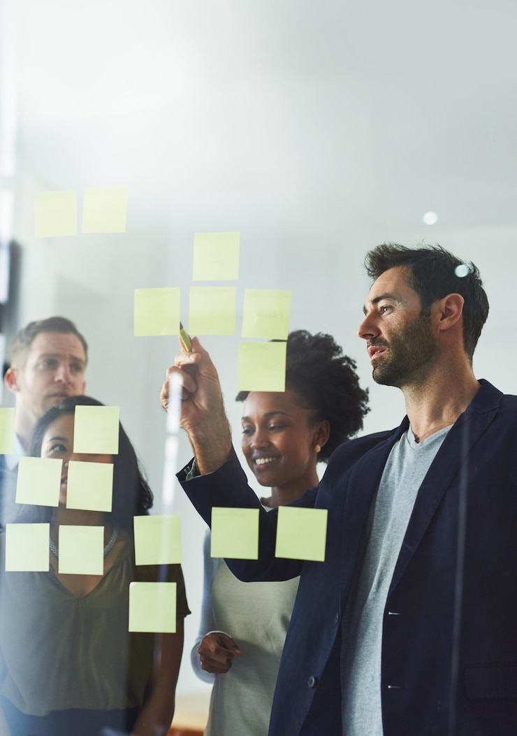 Foto escritura de ideias e pessoas de negócios em reunião para planejar discussão e brainstorming no escritório startup criativa e trabalhadores com notas adesivas na parede de vidro para pesquisa de trabalho em equipe e projeto