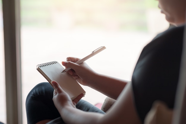 Escritura diestra de la mujer en la pequeña libreta