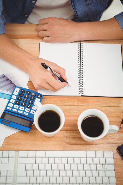 Escritura del inconformista en el cuaderno espiral en el escritorio en oficina