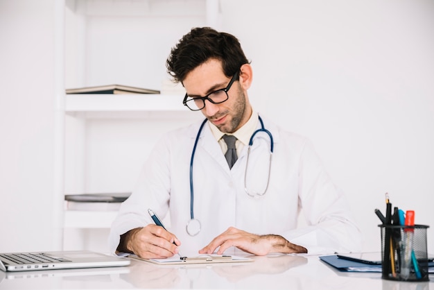 Escritura masculina del doctor en el tablero en hospital