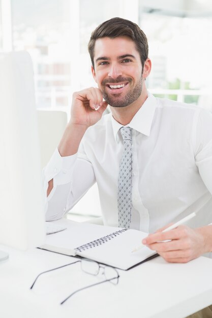 Escritura sonriente del hombre de negocios en la libreta