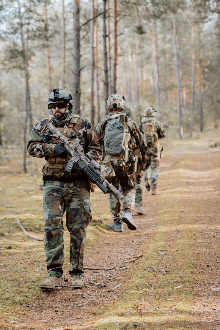 Escuadrón de cuatro soldados completamente equipados en camuflaje en una misión militar de reconocimiento