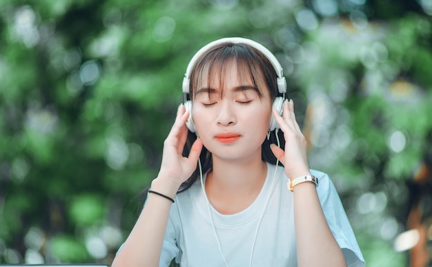 Escuchando música Una hermosa mujer con auriculares se relaja en su escritorio Cierra los ojos y medita meditar Ella está escuchando música usando el concepto de relajación y relajación de su teléfono inteligente