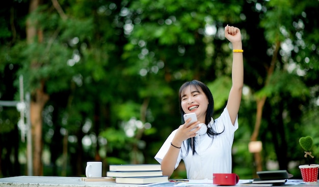 Escuchando música Una hermosa mujer con auriculares se relaja en su escritorio, sonríe y medita, medita. Ella está escuchando música usando el concepto de relajación y relajación de su teléfono inteligente.