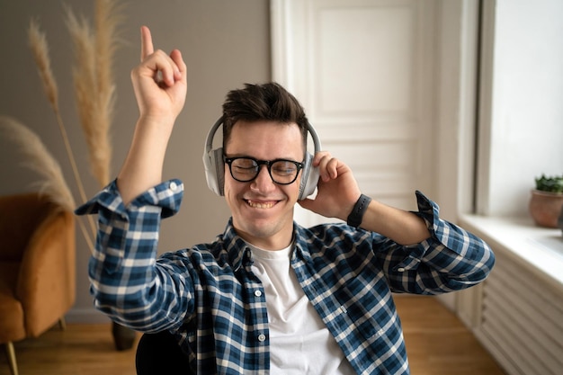 Escuchando música a todo volumen y bailando con auriculares inalámbricos un hombre feliz con gafas