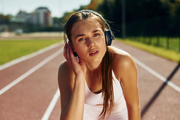 Escuchar música con auriculares Mujer joven con ropa deportiva hace ejercicio al aire libre