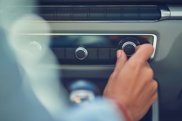 Escuchar música foto recortada de una mujer encendiendo la radio mientras conduce en la ciudad de cerca